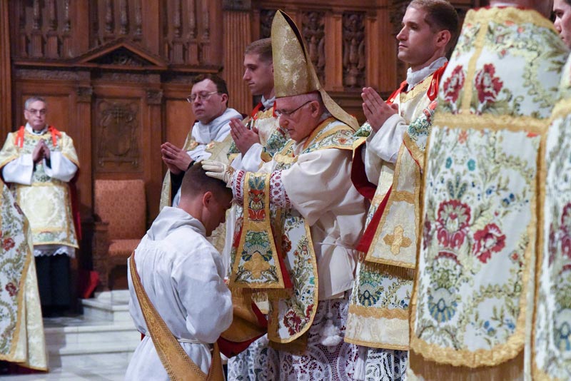 Das Photo zeigt den Moment, in dem Erzbischof Prendergast in der Kathedrale von Omaha einem der Kandidaten die Hände auflegt