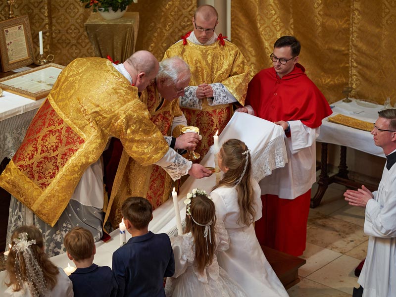 Die Aufnahme aus dem Jahr 2022 zeigt die fünf Kinder dieses Jahrganghs kniend an der Kommunionbank eim Empfang der Erstkommunion.