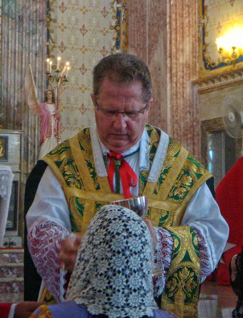 Bischof Rifan spendet einer an der Kommunionbank knienden Frau mit Schleier die hl. Kommunion