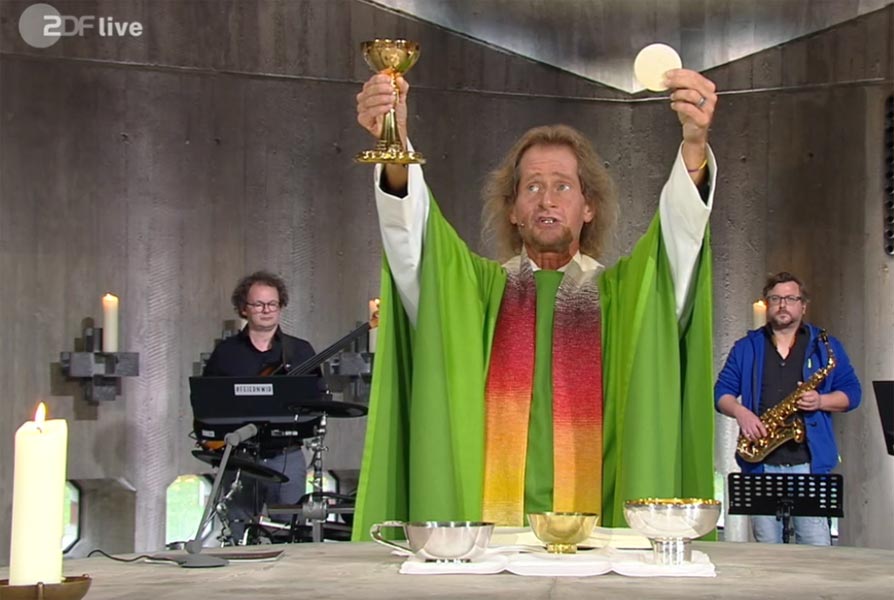 Der Zelebrant erhebt auf theatralische Weise die verwandelten Gestalten, um sie dem Publikum - so muß man das wohl nennren - zu präsentieren.