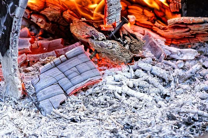 Das Das Photo zeigt die Asche eines heruntergebrannten Holzfeuers, unter der noch vereinzelte Glutstellen zu sehen sind